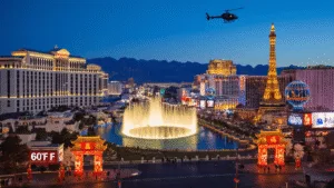 "Winter night cityscape of Las Vegas Strip with Bellagio fountains, Lunar New Year decorations, tourists, a helicopter tour and Red Rock Canyon in the background, under a 60°F clear sky."