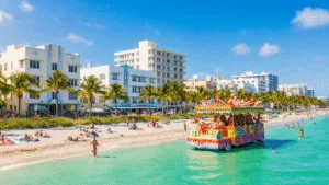 "Art Deco buildings and palm trees lining a Miami beach with sunbathers and swimmers in turquoise waters, under a clear sky in January, as a colorful King Mango Strut Parade float with costumed performers passes in the foreground."