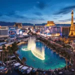 "Aerial view of Las Vegas at dusk with lit Strip, prominent landmarks, pool parties, the Red Rock Canyon backdrop, NASCAR race at Motor Speedway, digital billboards, and visitors enjoying outdoor activities"