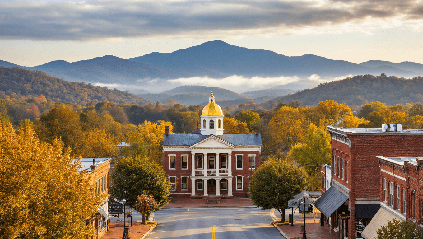 "Dahlonega's historic town square with gold-domed courthouse, surrounded by brick buildings and autumn foliage, with North Georgia Mountains in the background under a partly cloudy sky."