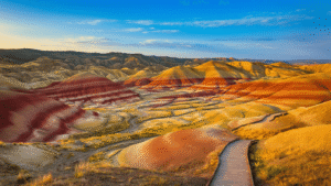 "Panoramic view of Painted Hills in Oregon at sunset, showcasing vibrant color striations and wooden boardwalk trail"